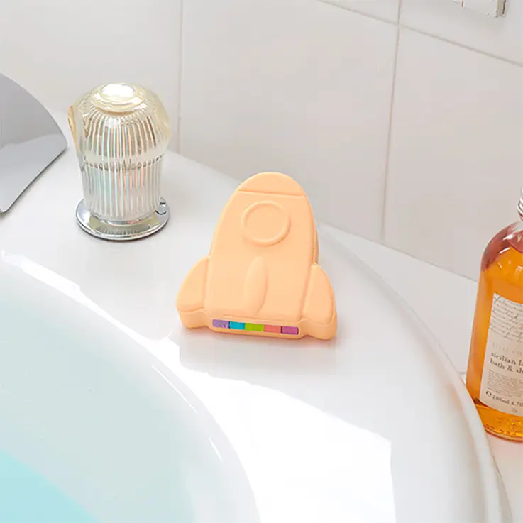 En forme de fusée, de couleur orange clair et au parfum d'abricot.